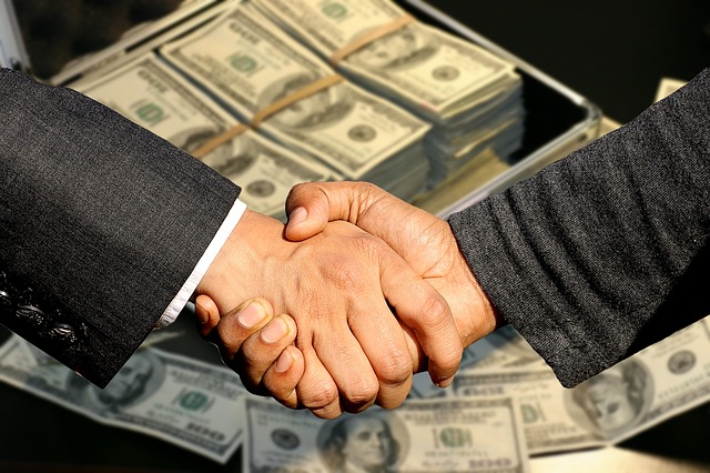 handshake in front of case of money