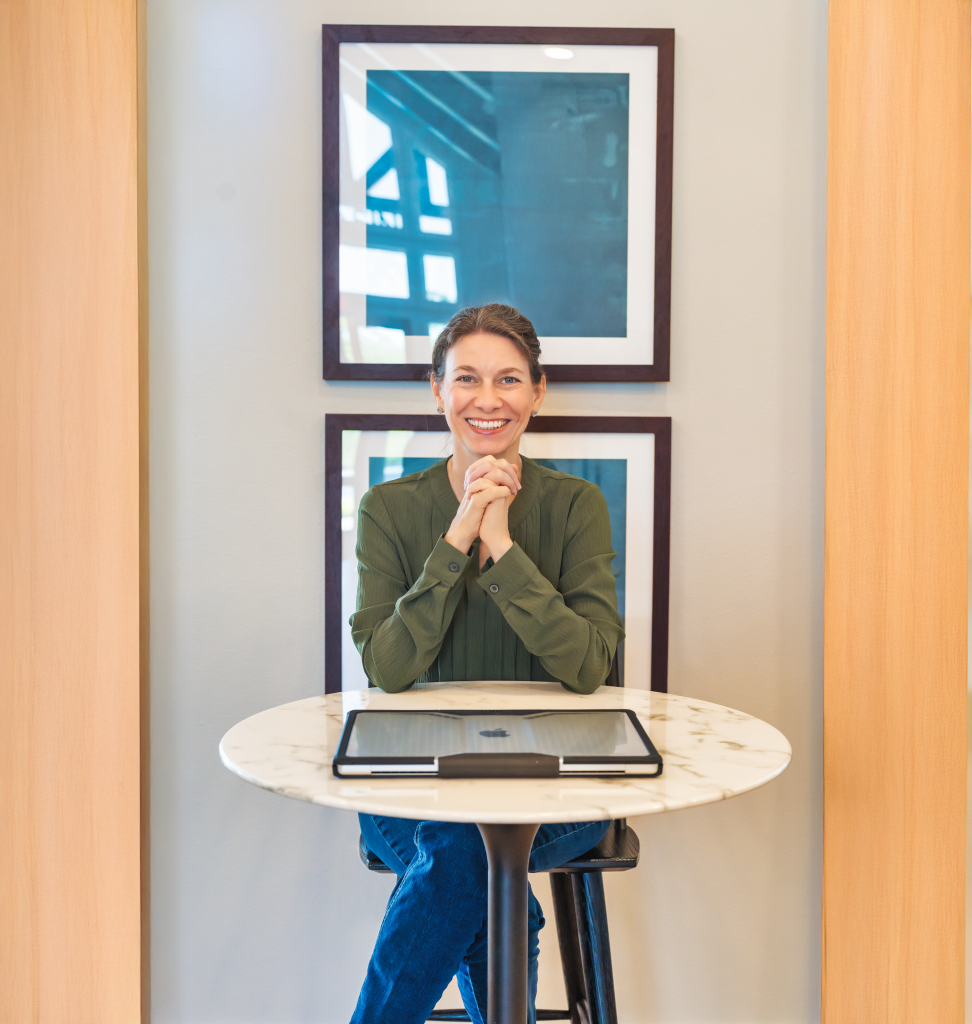 Alise smiling while seated at a small round table with a tablet